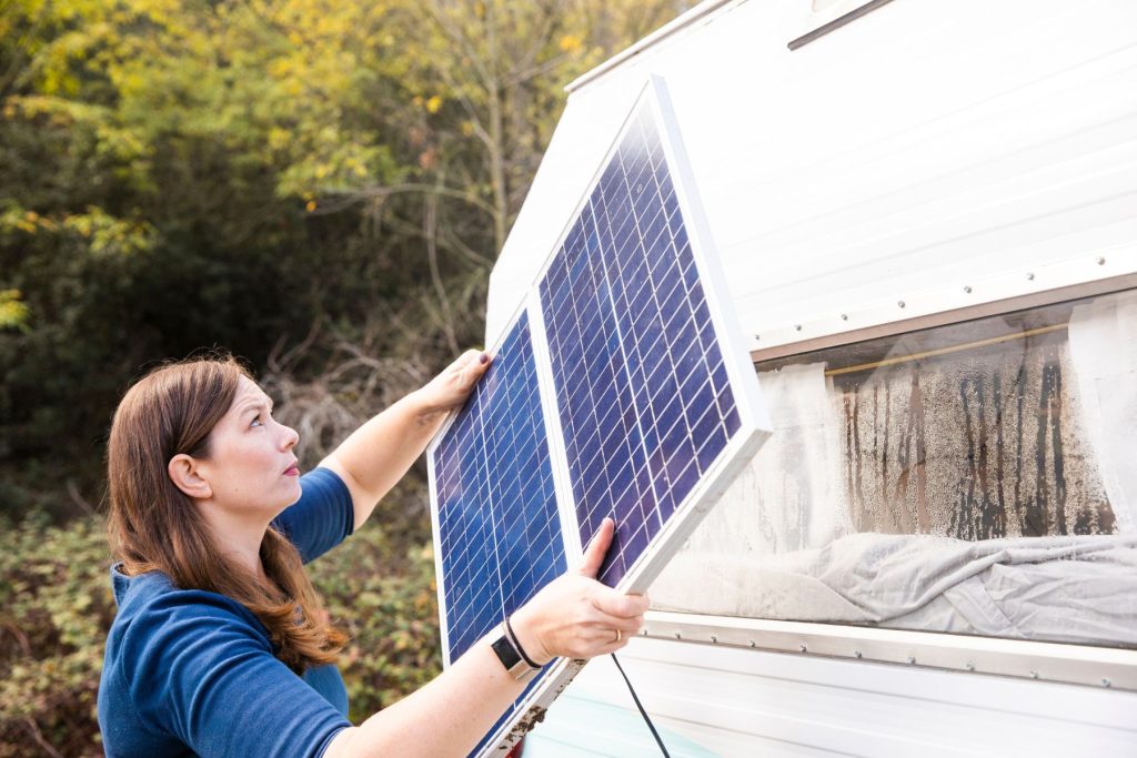 Woman installing solar panels on the side of her travel trailer