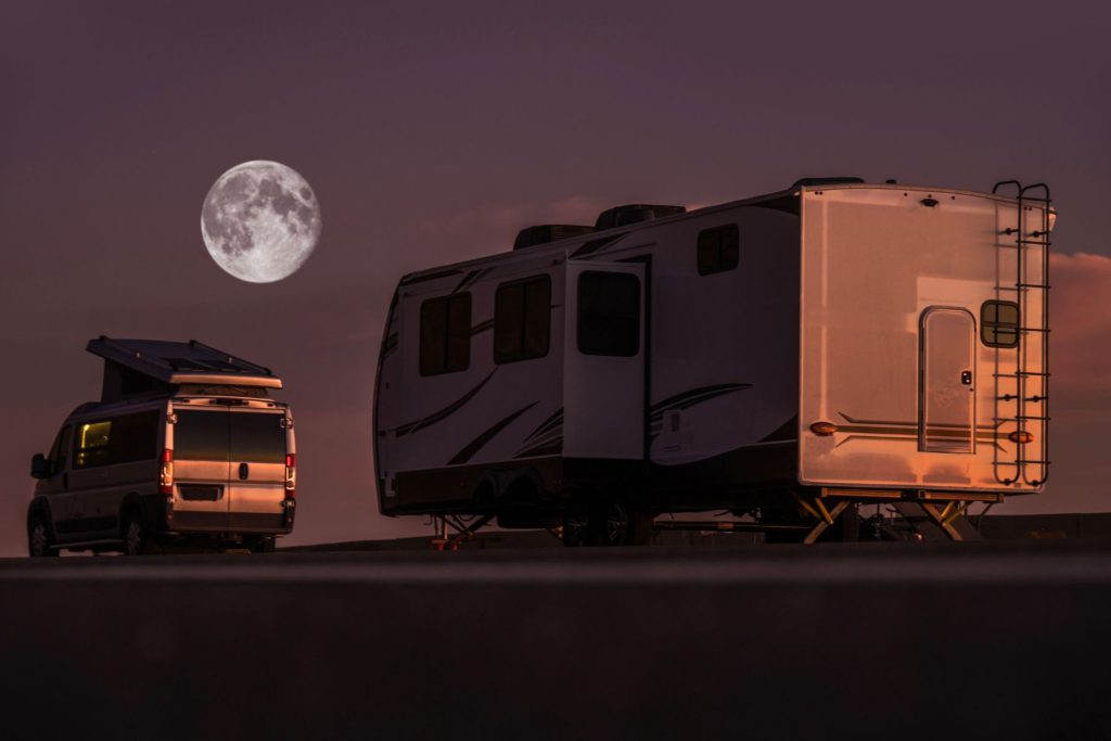 Motorhome and Travel Trailer side by side in an open area with the full moon visible in the background